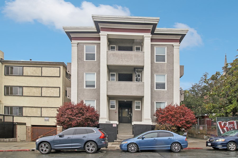 A grey car is parked in front of a building.
